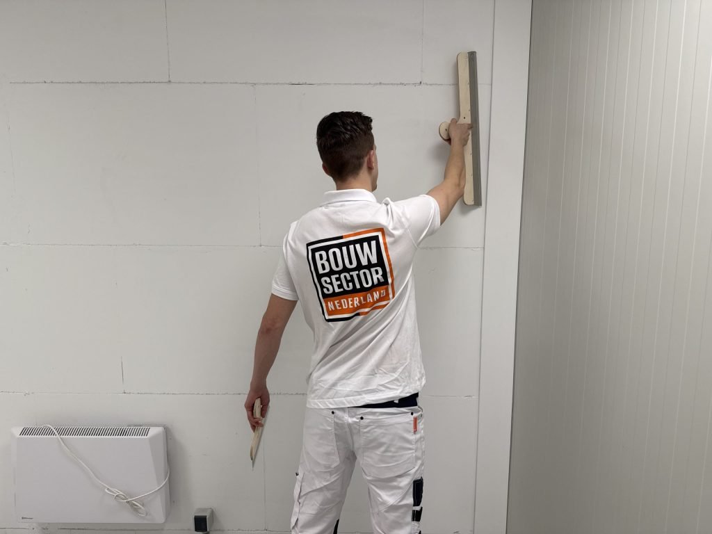 Stukadoor zet een spaan hoog tegen de wand om de nieuwe stuclaag vlak te trekken