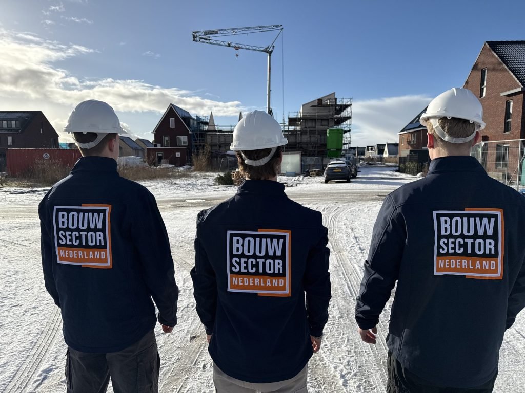 Drie vakmensen van Bouwsector Nederland met helm voor nieuwe woningen en een bouwkraan